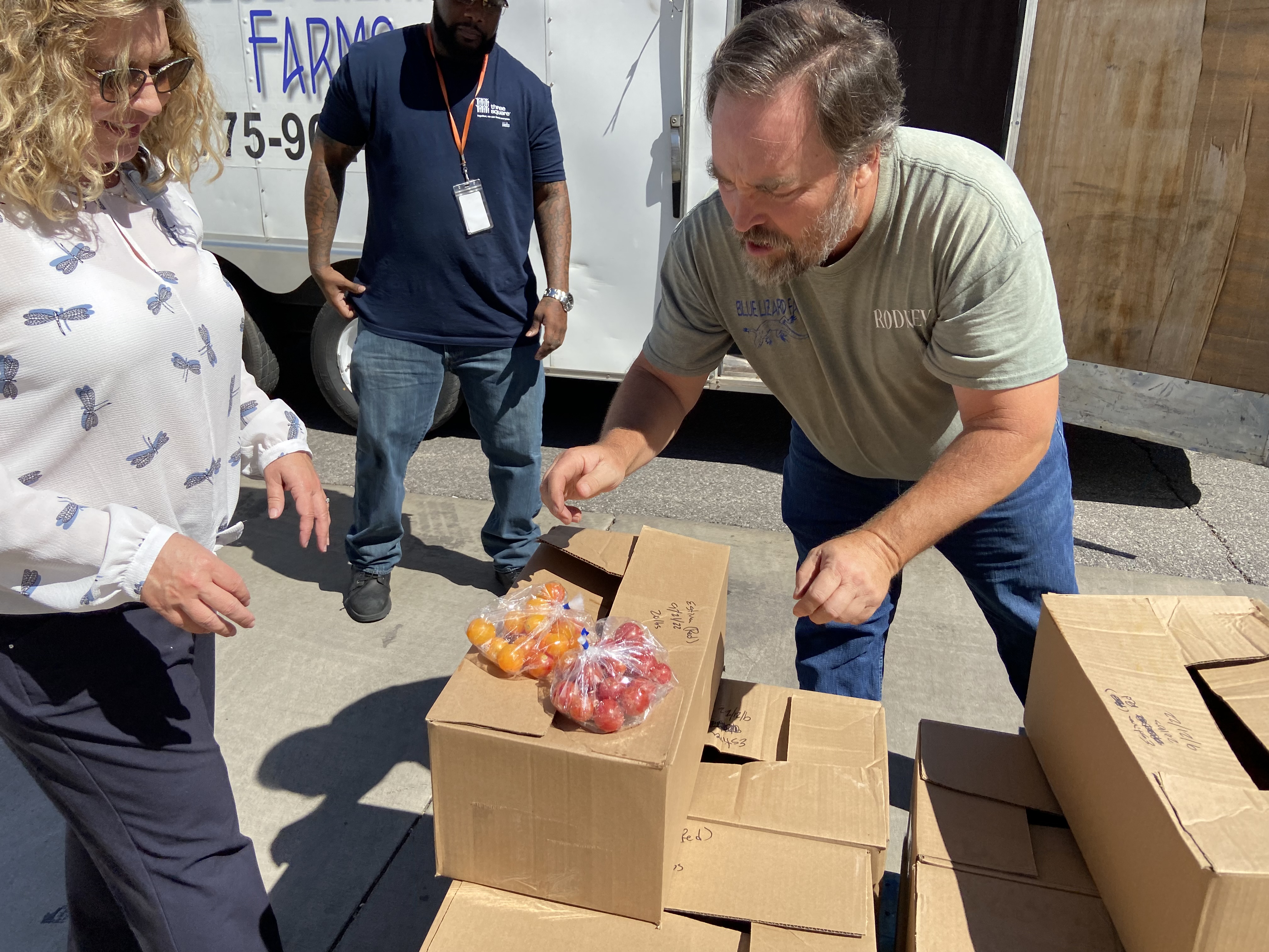 Rodney Mehring of Blue Lizard Farms shows representatives from Three Square Food Bank some of the tomatoes that are being delivered. 