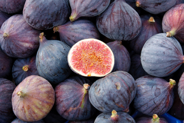 Close up photo of a pile of figs with one sliced open in the center.