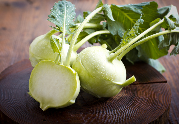 Photo of whole and sliced kohlrabi on a table.