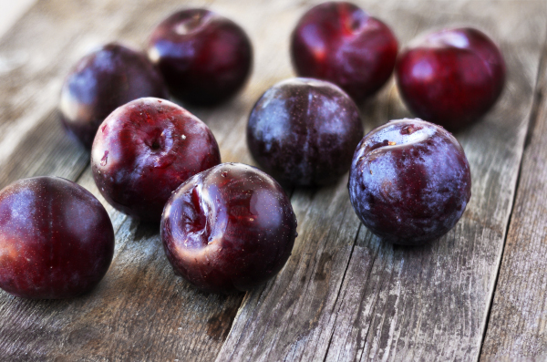 Photo of nine, freshly washed plums on a table. 
